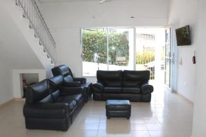 a living room with black leather furniture and a staircase at Casa moderna con piscina privada, Jacuzzi, Melgar Tolima in Melgar