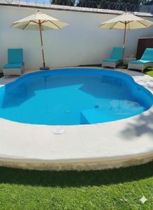 Villas Carlota Cancún في كانكون: مسبح ازرق كبير مع كرسيين ومظلات