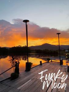Ein Holzsteg mit dem Sonnenuntergang im Hintergrund in der Unterkunft Funky Moon Kampot in Kampot