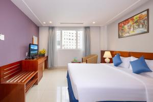 a bedroom with a large bed and a television at White Lotus Hotel Saigon in Ho Chi Minh City