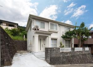 ein weißes Haus mit einem Zaun davor in der Unterkunft SAKURA HOUSE - Vacation STAY 07254v in Hakone