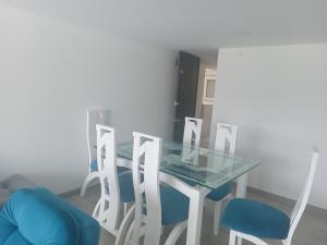 La mejor ubicación y tú mejor opción en Paipa في بايبا: طاولة طعام زجاجية مع أربعة كراسي زرقاء