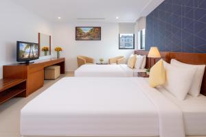 a hotel room with two beds and a television at White Lotus Hotel Saigon in Ho Chi Minh City +33 photos