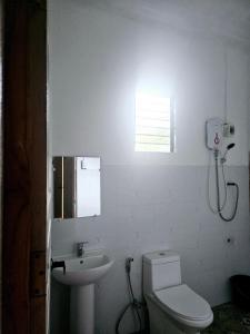 een witte badkamer met een toilet en een wastafel bij Rooms in Apo-estin in Cangatuyom