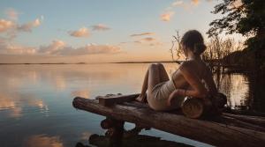 a woman sitting on a bench near a body of water at MBH Maya Bacalar Hotel Boutique in Bacalar