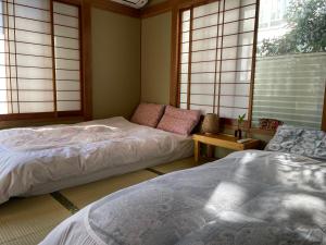 a bedroom with two beds and a couch and windows at Alia House 旅館 in Tokyo