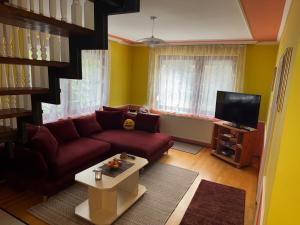 a living room with a red couch and a tv at Ili Vendégház in Zalakaros