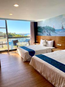 a hotel room with two beds and a large window at Kenting Waterfront Hotel in Kenting