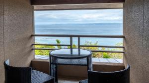 a table and chairs on a balcony with a view of the ocean at Hamachidorinoyu Kaisyu in Shirahama