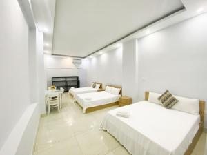 a white room with two beds and a table at Eco Hotel in Hanoi