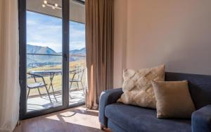 a living room with a couch and a balcony with a table at NEO Skyview Suites in Gudauri