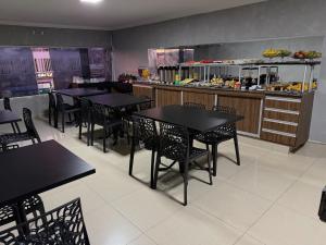 a restaurant with black tables and chairs and a counter at Hotel Nasser Aeroporto in Brasília