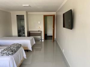 a room with two beds and a television on the wall at Hotel Nasser Aeroporto in Brasília +3 photos