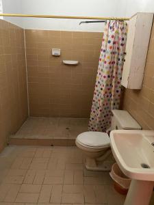 a bathroom with a toilet and a shower curtain at Finca La Camila in Coello
