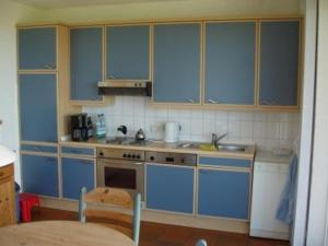 una cucina con mobili blu e un lavandino di Doppelhaushälfte Poppinga a Baltrum