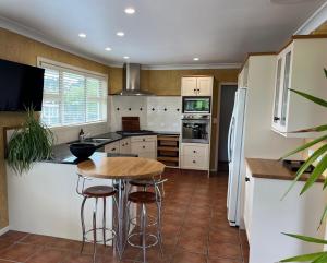 una cucina con tavolo e sgabelli di Mount Taranaki Basecamp 4BR Farmhouse & Games Room 