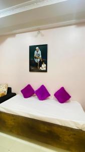 ein Bett mit lila Kissen und einem Bild an der Wand in der Unterkunft Silver ok appartment in Shirdi