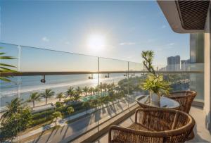 einen Balkon mit einem Tisch und Stühlen sowie Strandblick in der Unterkunft Peninsula Hotel Danang in Đà Nẵng