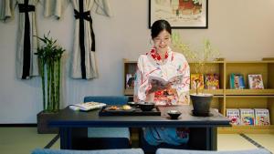 a woman in a kimono standing next to a table at Mitasuya Ryokan Hotel by Anook Pyeongtaek Station in P'yŏngt'aek +142 photos