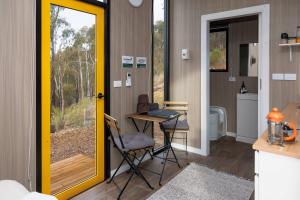 Casa pequeña con mesa y baño en The Bunjil by Tiny Away, en Steels Creek