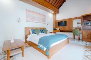 a bedroom with a bed and a desk and a tv at Kania Rooms & Suite in Seminyak