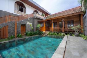 a swimming pool in front of a house at Kania Rooms & Suite in Seminyak