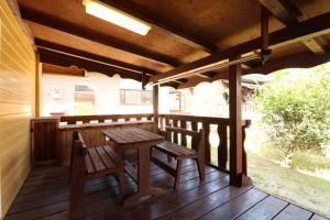 eine Holzterrasse mit einem Tisch und Bänken auf einer Terrasse in der Unterkunft ウィークリー宿家里 in Akaren