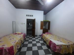 two beds in a room with a checkered floor at Hospedaje Sadicita in Requena
