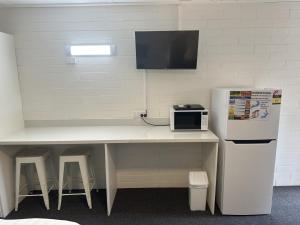 cocina con mesa, microondas y nevera en Vineland Motel Mildura, en Mildura