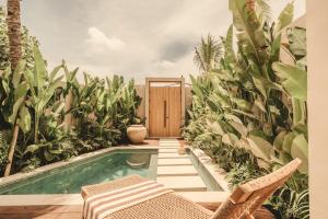 a pool in a garden with chairs and plants at NORI Boutique Villas Uluwatu - Breakfast Available in Uluwatu