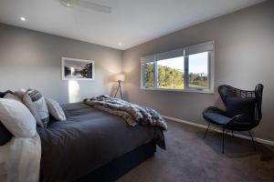 a bedroom with a bed and a chair and a window at The Welcome Paddock in Hepburn