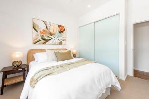 Un dormitorio con una cama blanca y un cuadro en la pared. en Keesing Villa 7, en Byron Bay