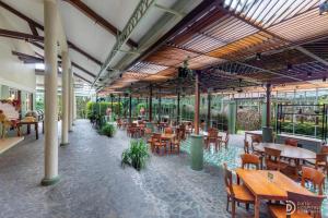 a restaurant with wooden tables and chairs and plants at Hotel Grand Panorama Lembang in Lembang
