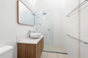 バイロンベイにあるKeesing Villa 8の洗面台と鏡のある白いバスルーム +1枚の写真
