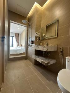 un bagno con lavandino, specchio e letto di Anh Khoa Hotel a Kon Tum