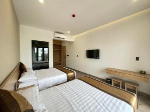 due letti in una stanza con una TV a parete di Anh Khoa Hotel a Kon Tum