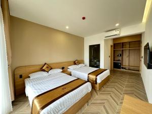 una camera d'albergo con due letti e una televisione di Anh Khoa Hotel a Kon Tum