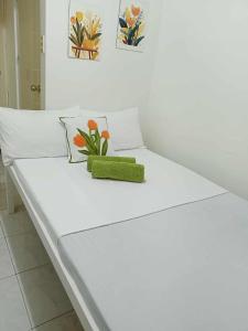 een wit bed met een groen kussen en bloemen erop bij Liberty's Homestay in Coron