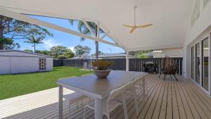 eine Terrasse mit einem weißen Tisch und Stühlen auf einer Terrasse in der Unterkunft Luxe Hideaway - South Umina in Umina