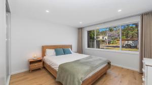 ein Schlafzimmer mit einem Bett und einem großen Fenster in der Unterkunft Luxe Hideaway - South Umina in Umina
