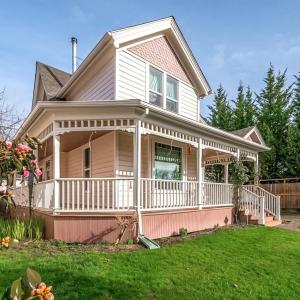 une maison avec une terrasse couverte et une pelouse dans l'établissement The Pink House - Pets OK Victorian Near 3rd Street, à McMinnville