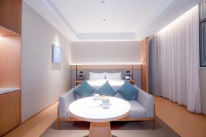 ein Hotelzimmer mit einer Couch und einem Tisch in der Unterkunft JI Hotel Shenzhen Bantian Huawei Base in Shenzhen