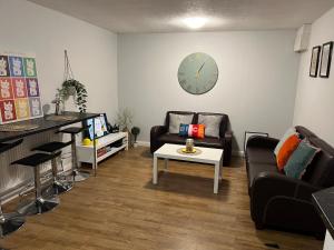 ein Wohnzimmer mit einer Couch, einem Tisch und einer Uhr in der Unterkunft Rare 4 en-suite Bedroom Flat with Free Parking and workspace in Warwick