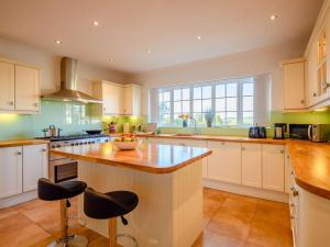 una cucina con armadi bianchi e un'isola con sgabelli da bar di 4 Bed in Bridport 89788 a Corscombe