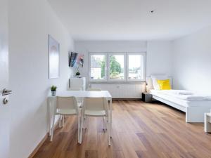 ein weißes Zimmer mit einem Tisch, Stühlen und einem Bett in der Unterkunft BudgetRoom 3 Schlafzimmer Workers Home in Marl