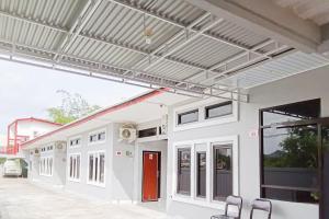 Un edificio blanco con toldo y sillas en un patio. en RedDoorz near Bandara Depati Amir,  8 fotos más