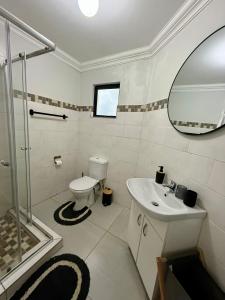 a bathroom with a toilet and a sink and a mirror at The Minimalist Suite in Kempton Park