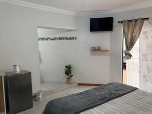 a bedroom with a bed and a television on the wall at The Minimalist Suite in Kempton Park