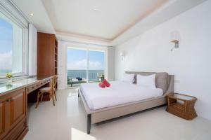 Waterfront 16D seaview 2 BR apartment - 5 min walk to Karon beach في شاطئ كارون: غرفة نوم بها سرير ومكتب ونافذة +27 صورة