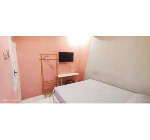 Un pequeño dormitorio con una cama y un televisor. en OYO 95042 Jasmine Guest House, en Karangtengah